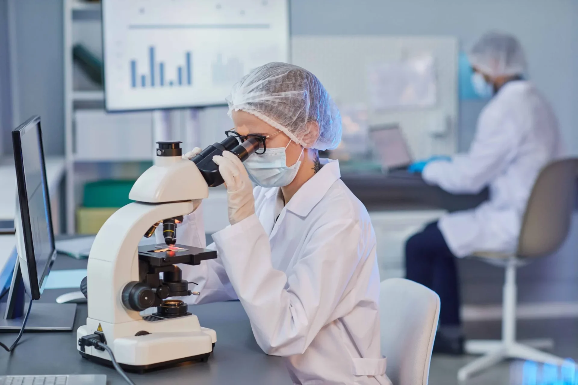 Researcher examining enclomiphene sample under microscope in laboratory setting.