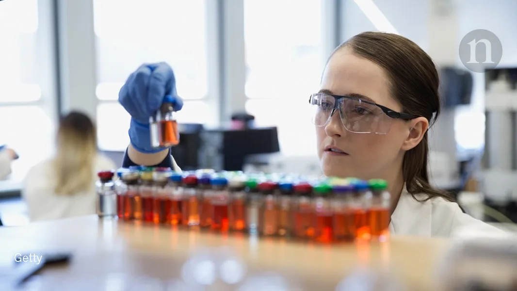 Scientist examines vials with orange liquid in a laboratory, emphasizing ostarine research on liver toxicity.