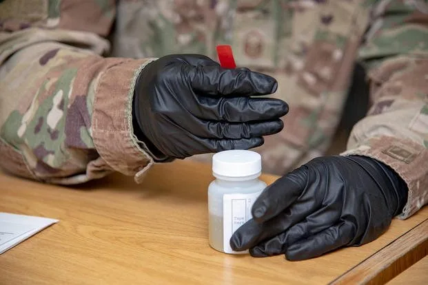 military researcher handling sample jar for sarms analysis in a laboratory.